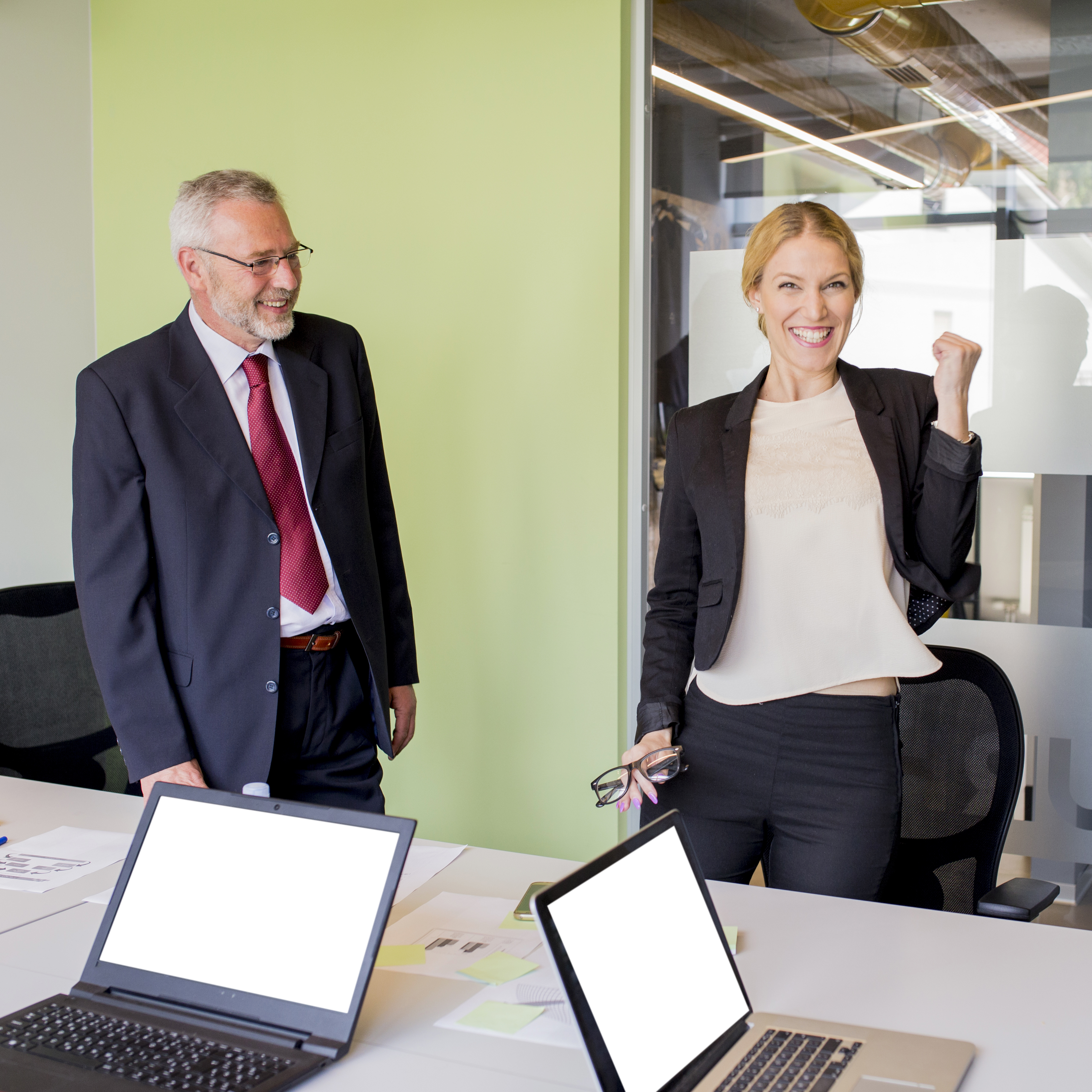 mature-businessman-looking-successful-happy-young-businesswoman-clenching-her-fist